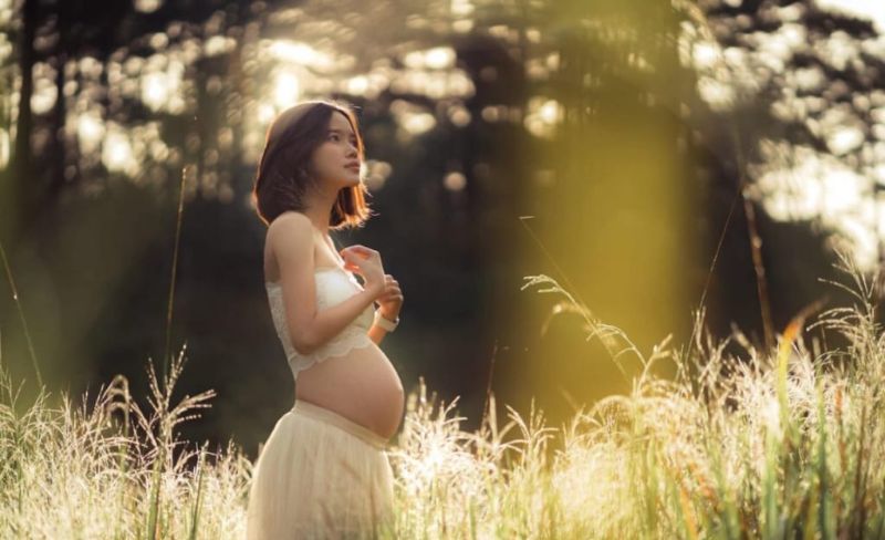 ngườ phụ nữ mang thai đang đứng một mình ở dodongf cỏ
